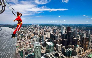 A brave reporter leans over the edge of the catwalk during the media preview for the "EdgeWalk" on the CN Tower in Toronto, July 27, 2011. Participants are strapped in to a harness that is attached to a guard rail while walking around the catwalk on the structure 1,168 feet above the ground.